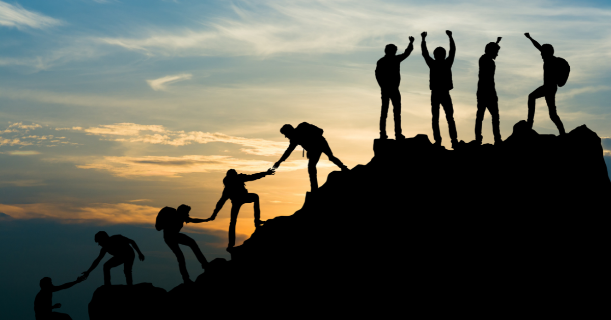 People extended a hand to help each other up a mountain